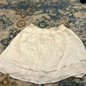 A mid thigh length white skirt with ruffles at the bottom.